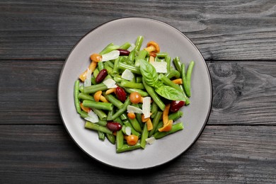 Photo of Delicious salad with green beans, mushrooms and cheese on black wooden table, top view