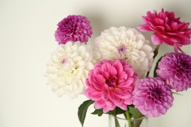 Photo of Bouquet of beautiful Dahlia flowers near white wall, closeup