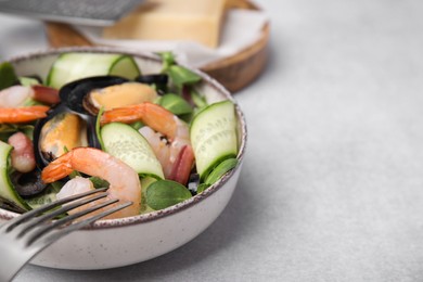 Photo of Bowl of delicious salad with seafood on light grey table, space for text