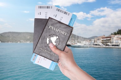 Image of Woman holding international passports with boarding passes and beautiful view of boats in sea near shore on background