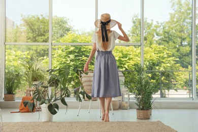 Photo of Woman with straw hat at indoor terrace, back view