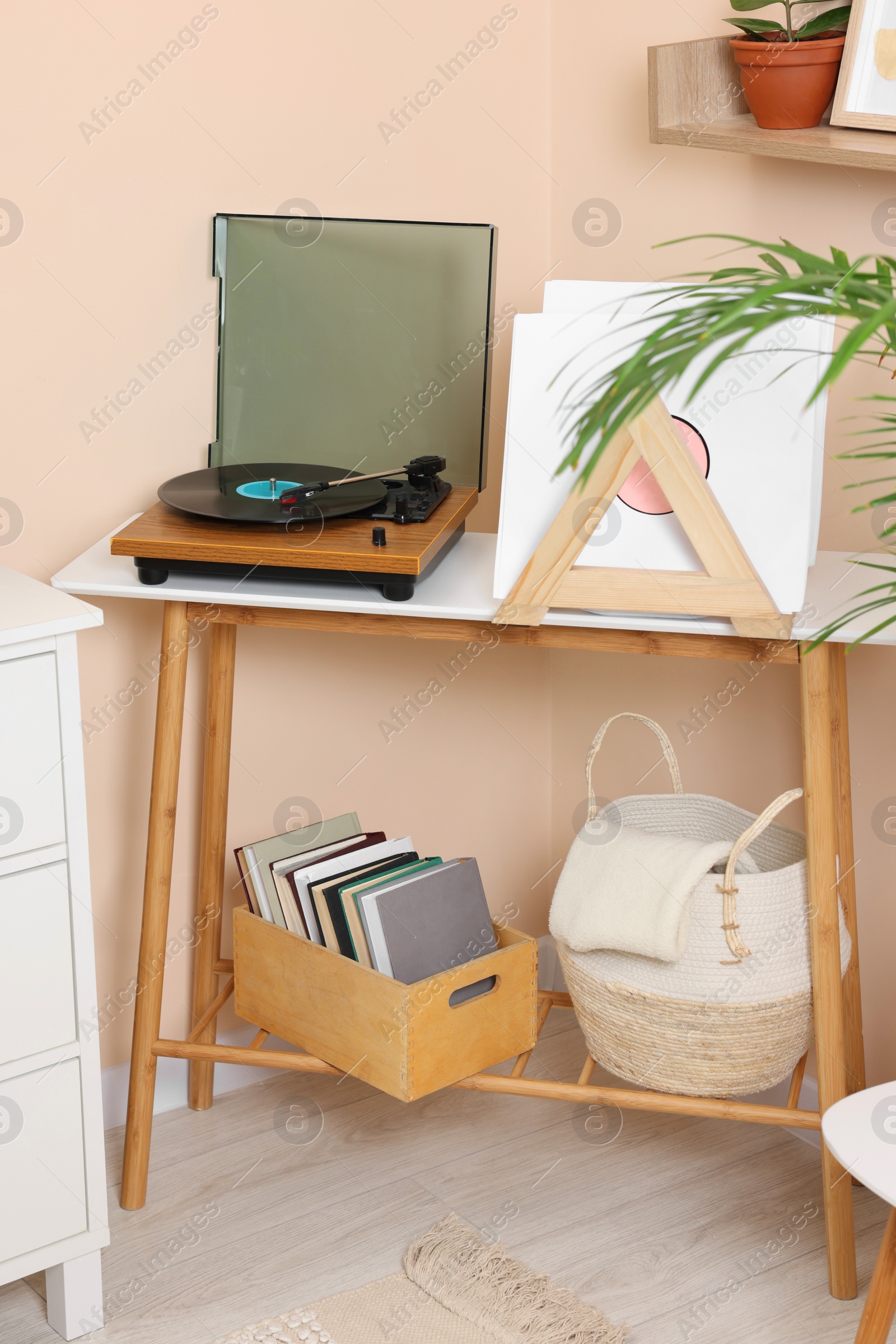 Photo of Stylish turntable with vinyl record on console table in cozy room