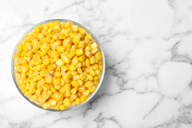 Delicious canned corn in bowl on marble table, top view. Space for text