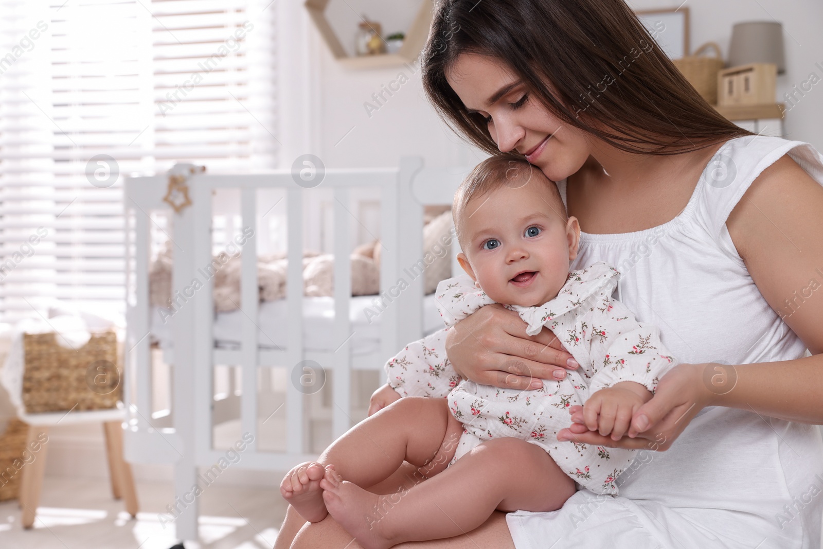 Photo of Happy young mother with her baby daughter in nursery. Space for text