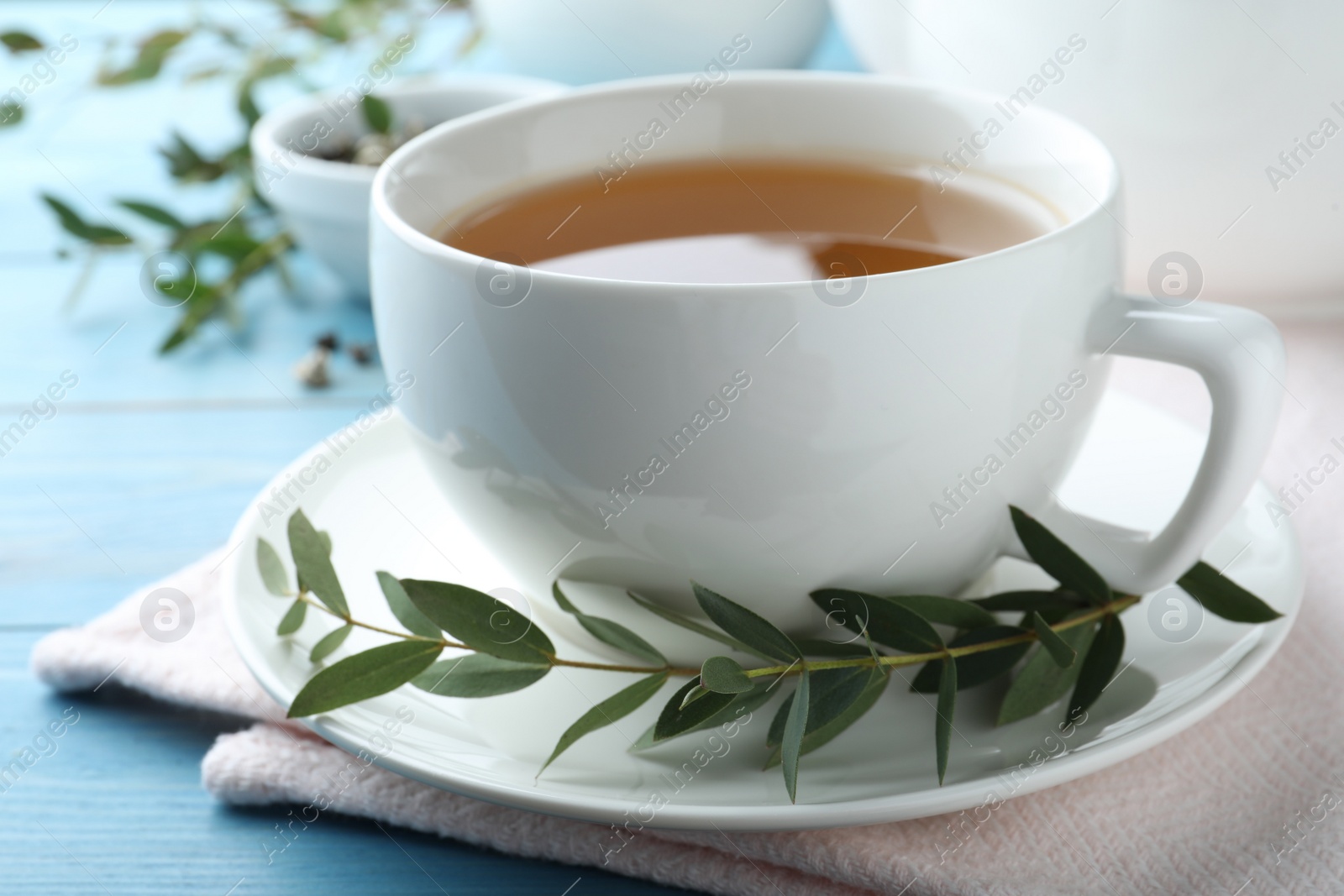 Photo of Cup of aromatic eucalyptus tea on light blue wooden table, closeup