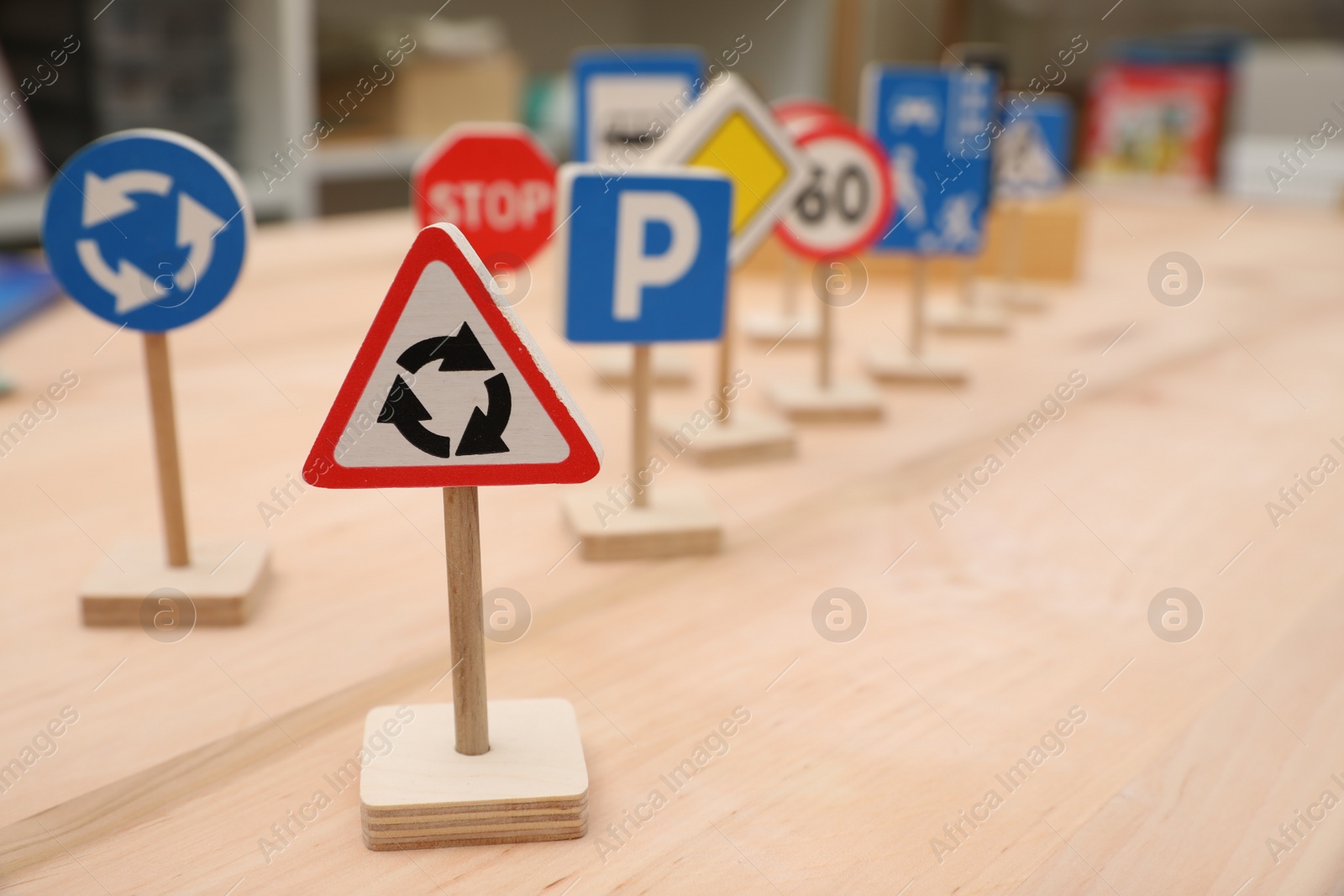 Photo of Different miniature road signs on wooden table, space for text. Montessori toy