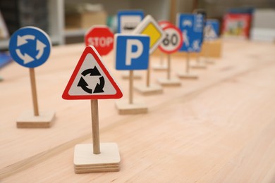 Photo of Different miniature road signs on wooden table, space for text. Montessori toy