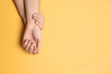 Woman showing golden manicure on color background, top view with space for text. Nail polish trends