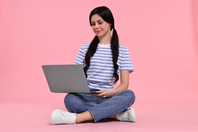 Student with laptop sitting on pink background