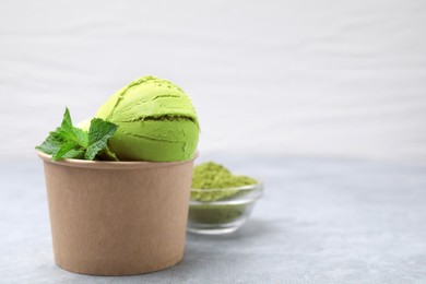 Paper cup with tasty matcha ice cream on grey table. Space for text