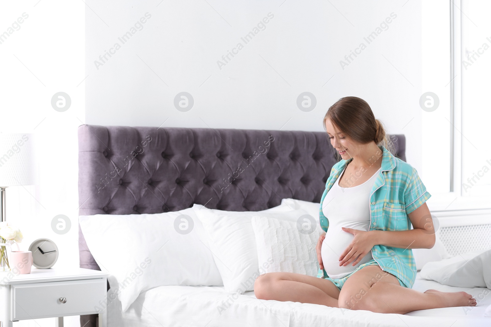 Photo of Pregnant woman sitting in bed at home