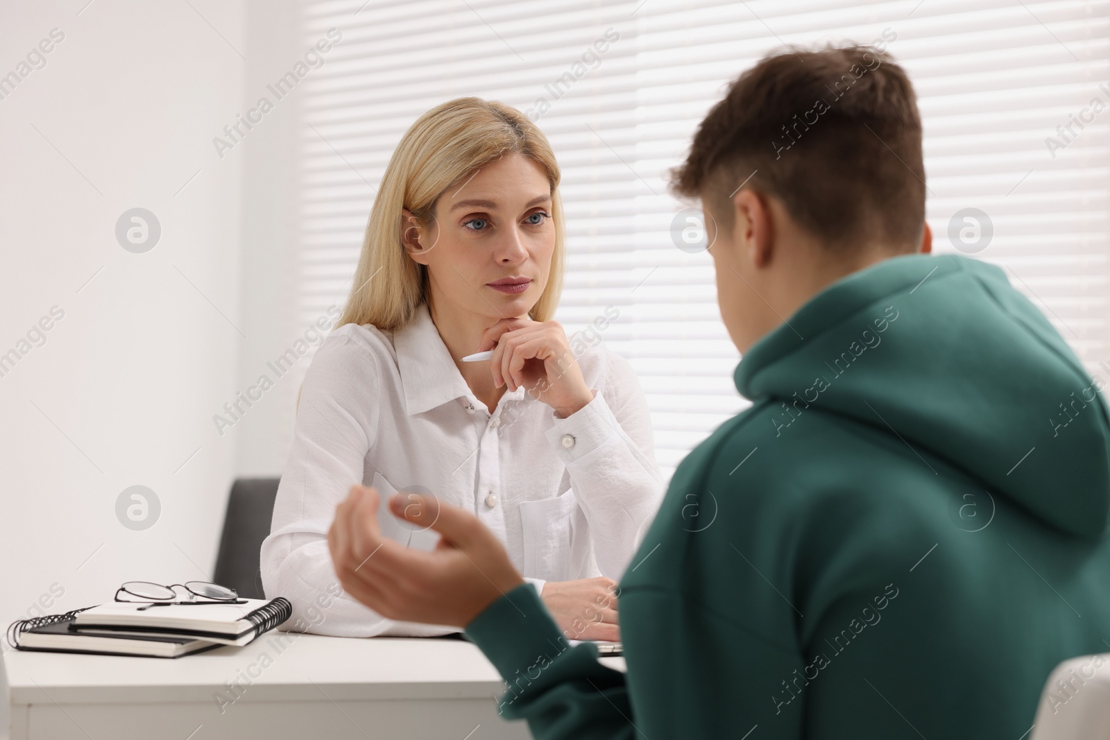 Photo of Psychologist working with teenage boy at table in office