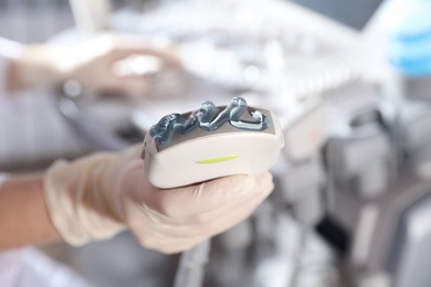 Photo of Sonographer holding ultrasound machine probe with gel in clinic, closeup