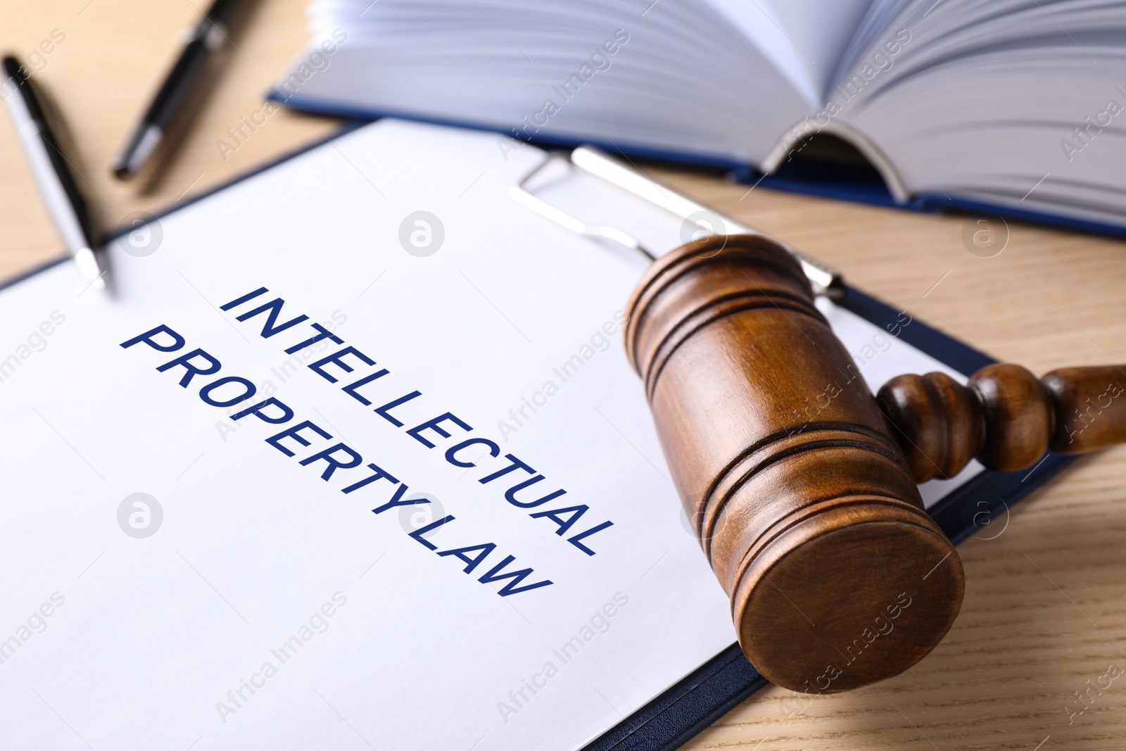 Image of Clipboard with words Intellectual Property Law and judge's gavel on wooden table, closeup