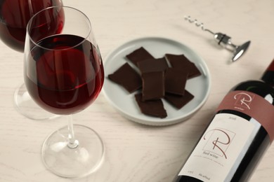 Photo of Tasty red wine and chocolate on white wooden table