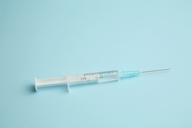 Photo of One medical syringe on light blue background