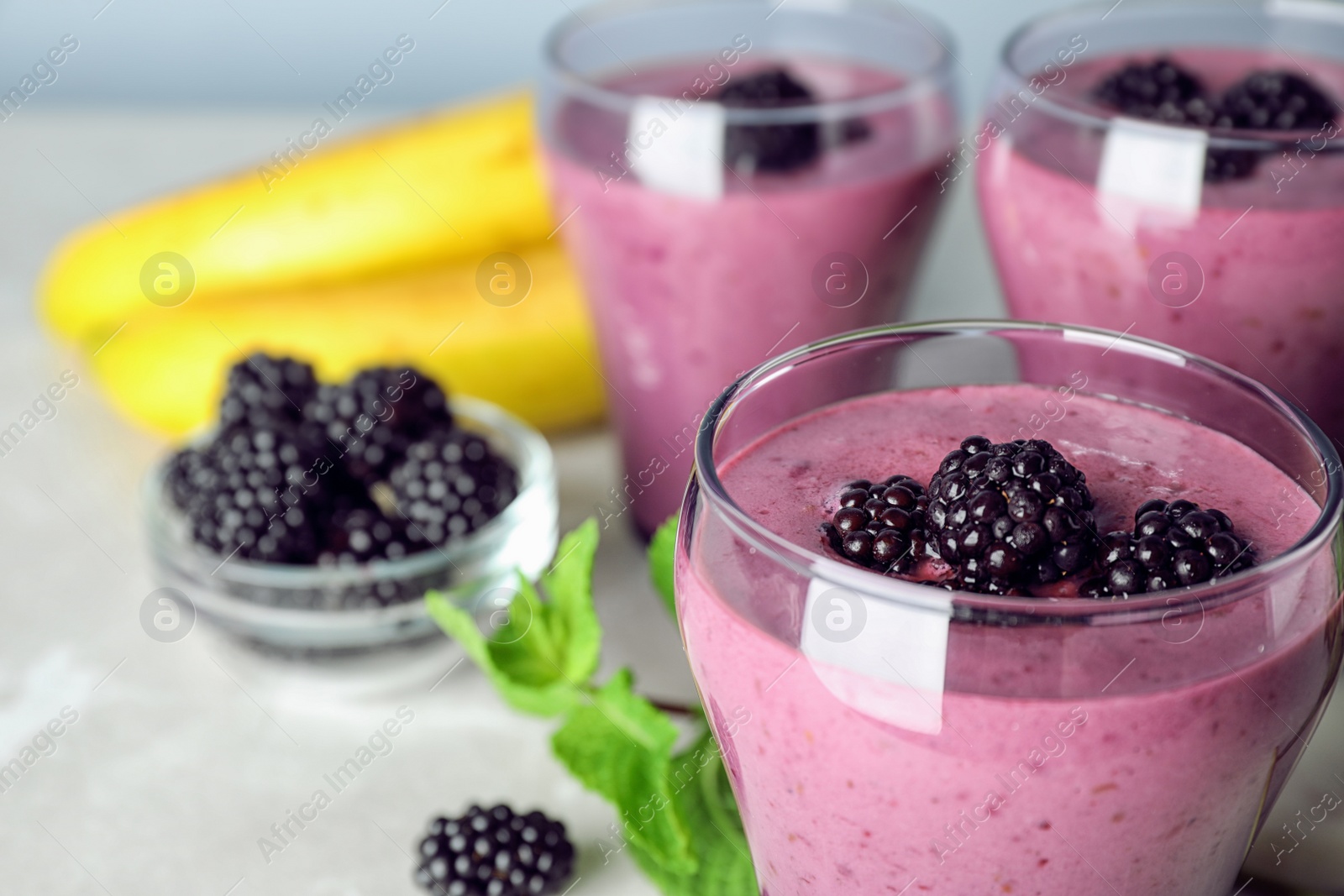 Photo of Delicious blackberry smoothie in glasses and ingredients on table, closeup