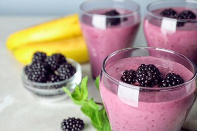 Delicious blackberry smoothie in glasses and ingredients on table, closeup