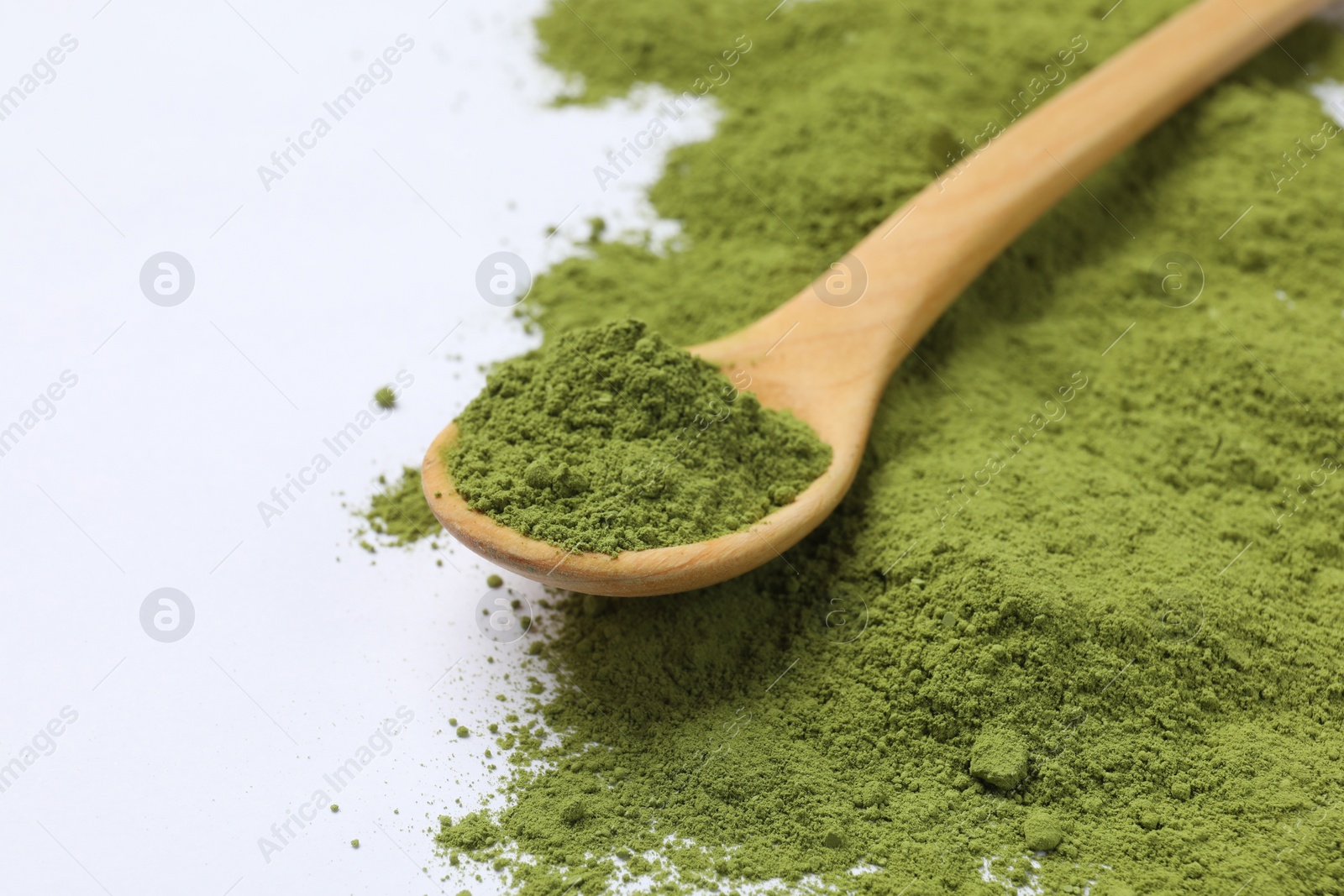 Photo of Green matcha powder and wooden spoon isolated on white