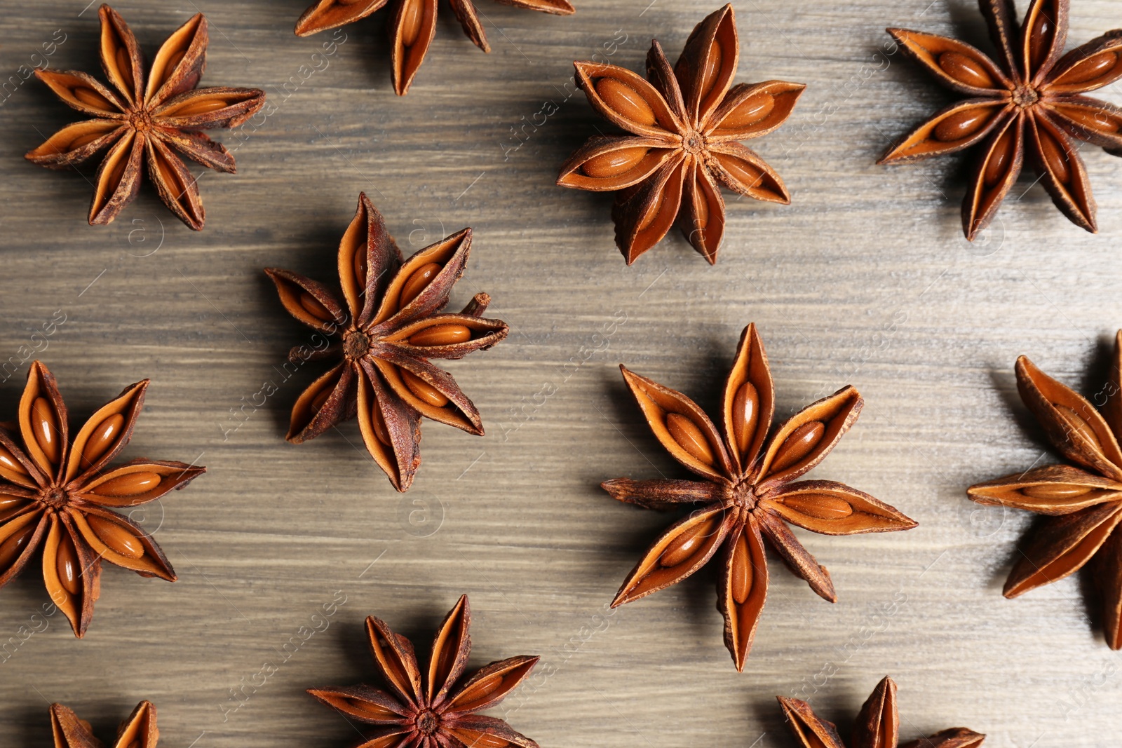 Photo of Aromatic anise stars on wooden table, flat lay