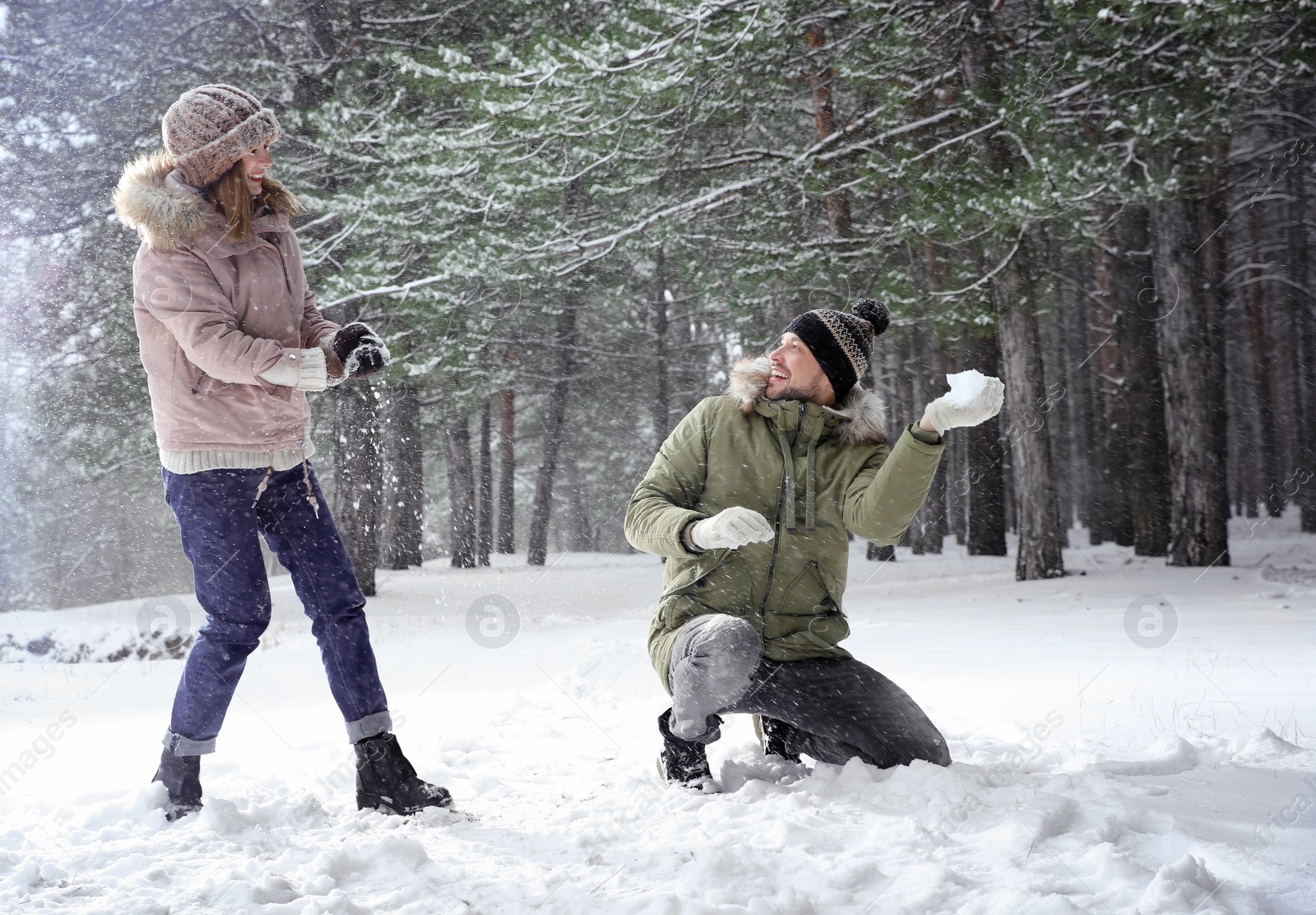 Photo of Happy couple playing snowballs in winter forest