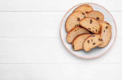 Plate of sweet hard chuck crackers with raisins on white wooden table, top view. Space for text