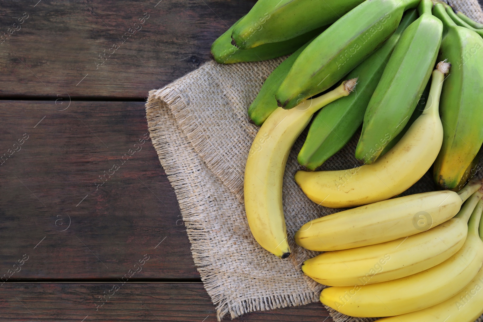 Photo of Different sorts of bananas on wooden table, flat lay. Space for text