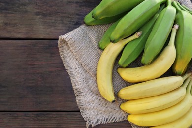 Photo of Different sorts of bananas on wooden table, flat lay. Space for text