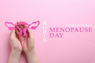 World Menopause Day - October, 18. Woman holding paper uterus on pink background, top view