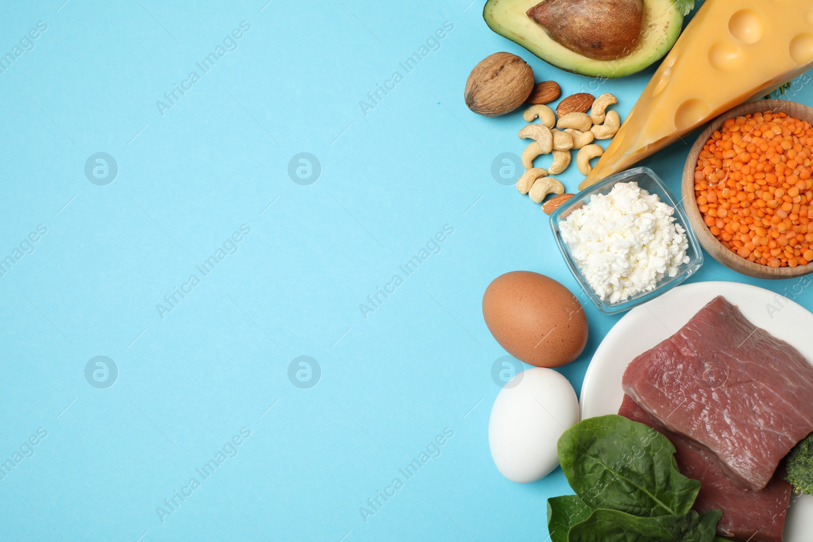 Photo of Different products rich in protein on light blue background, flat lay. Space for text