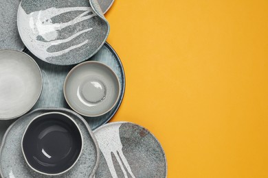 Photo of Different plates and bowls on yellow background, flat lay. Space for text