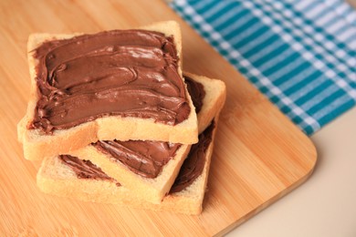 Photo of Tasty toasts with chocolate paste on beige table, space for text