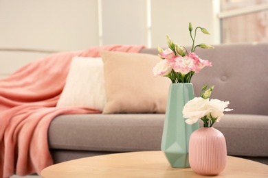 Beautiful flowers in vases and space for text on blurred background. Element of interior design