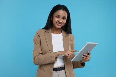 Photo of Beautiful secretary with tablet on light blue background