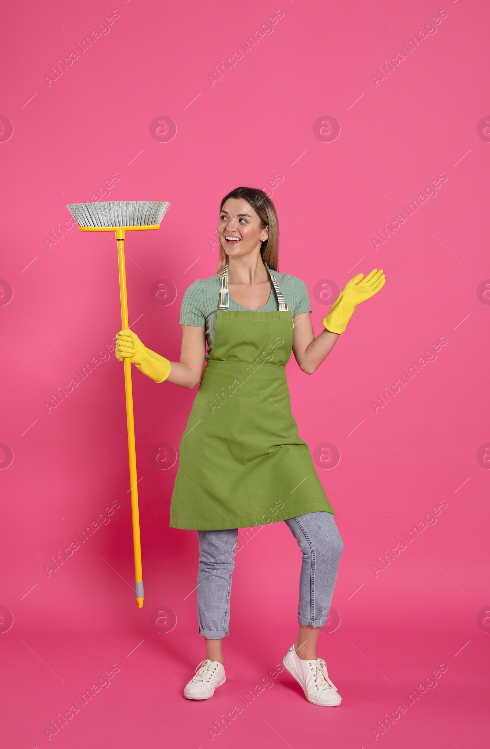 Photo of Young woman with yellow broom on pink background