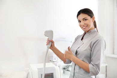 Young woman holding professional laser epilator in beauty salon