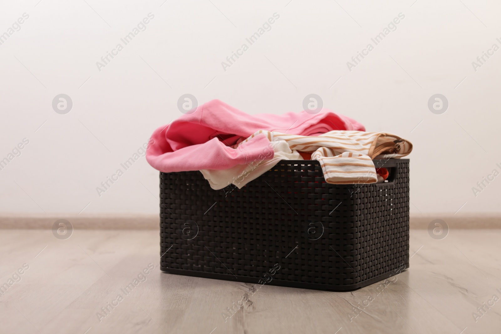Photo of Laundry basket with dirty clothes on floor