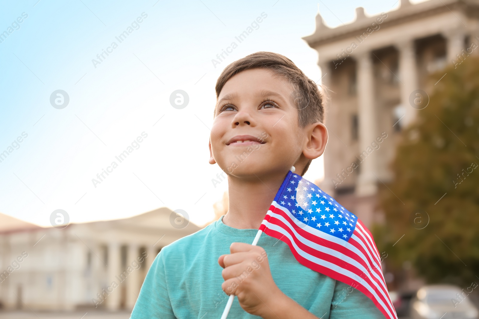 Photo of Cute little boy with American flag on city street