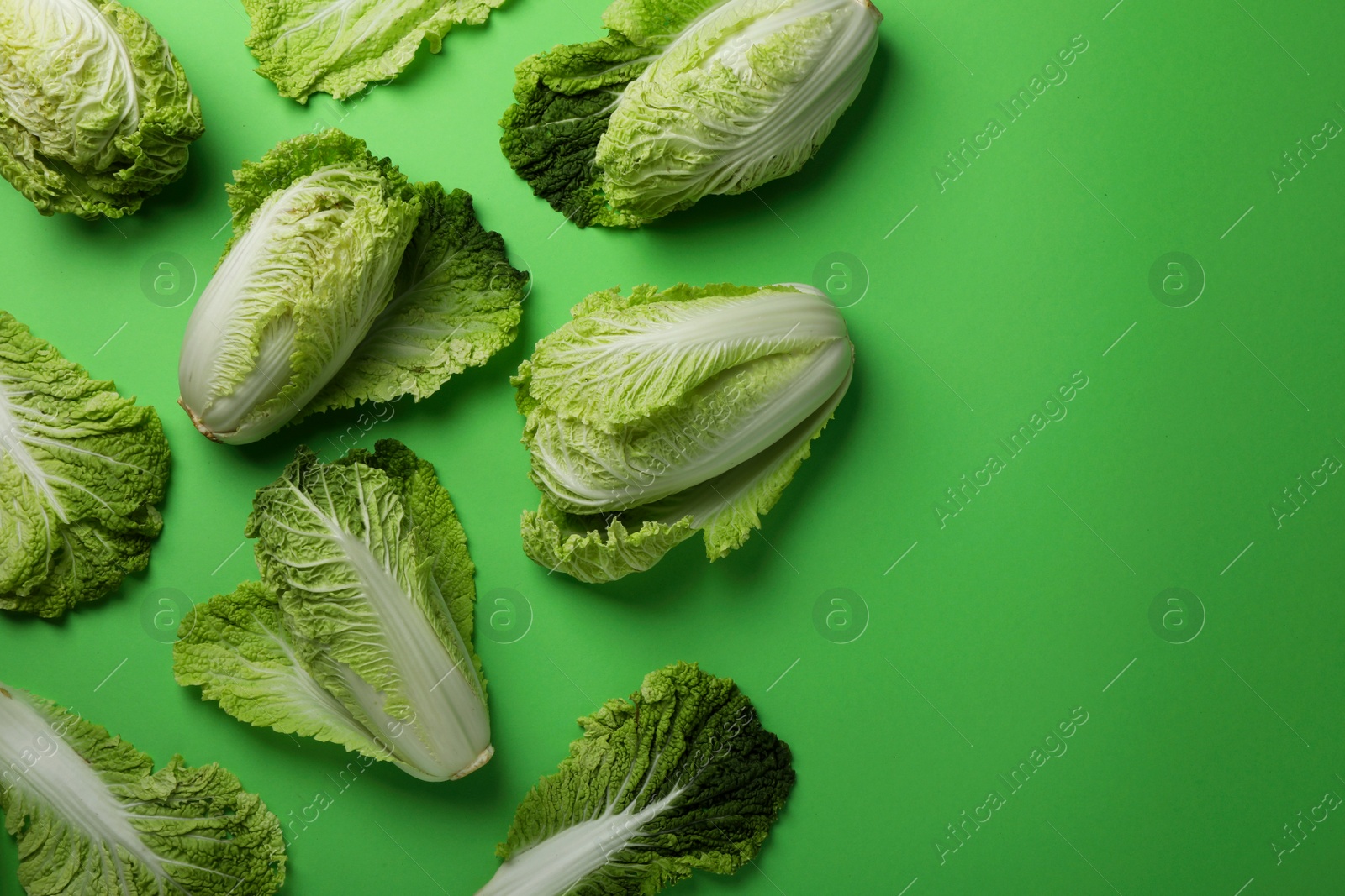 Photo of Fresh ripe Chinese cabbages on light green background, flat lay. Space for text