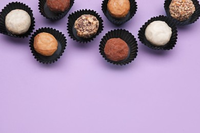 Tasty chocolate candies on violet background, flat lay. Space for text