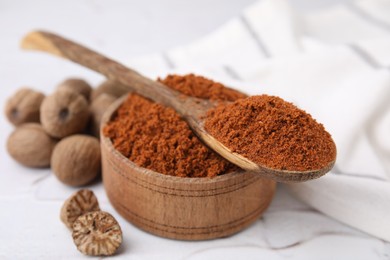 Photo of Nutmeg powder and seeds on white table, closeup