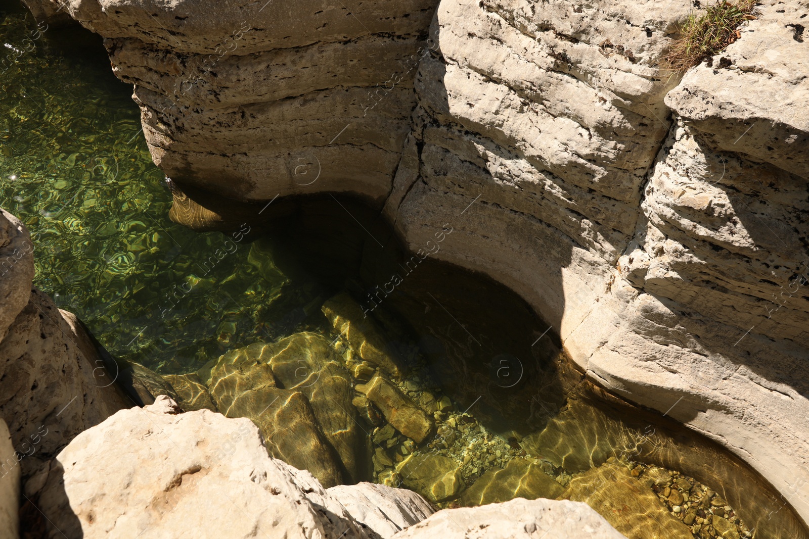 Photo of Beautiful clean pond between big rocks outdoors