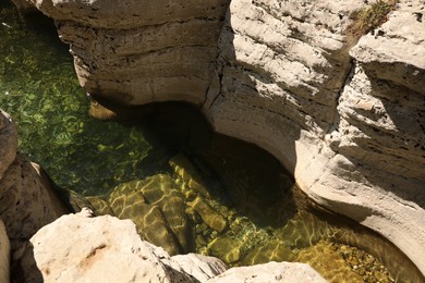 Photo of Beautiful clean pond between big rocks outdoors