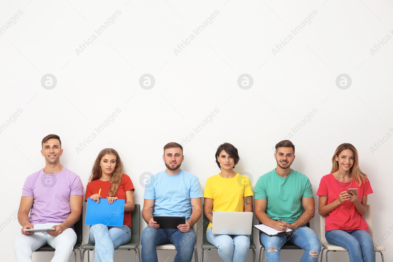 Photo of Group of young people waiting for job interview near light wall