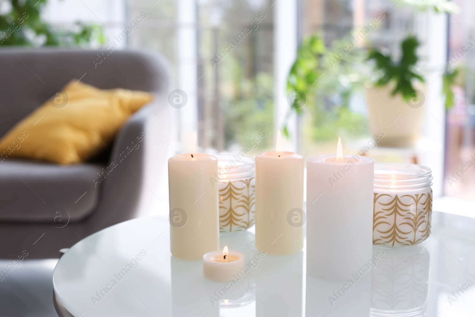 Photo of Burning candles on table indoors. Interior decor element