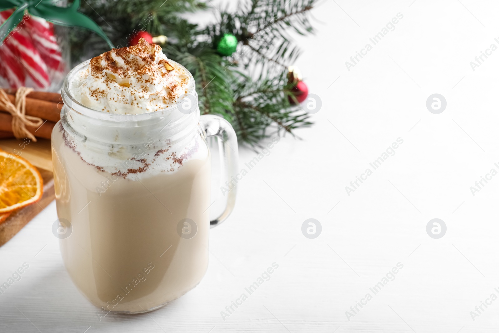 Photo of Delicious Christmas liqueur with whipped cream on white table, closeup. Space for text