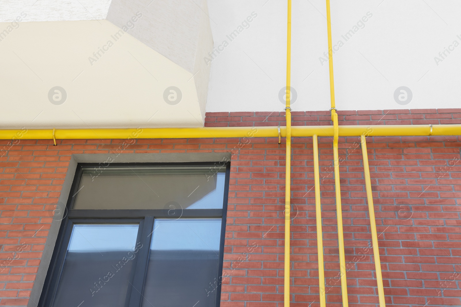 Photo of Yellow gas pipes on red brick wall outdoors