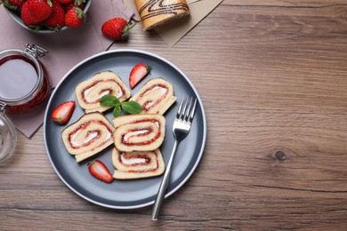 Photo of Tasty cake roll with strawberry jam and cream on wooden table, flat lay. Space for text