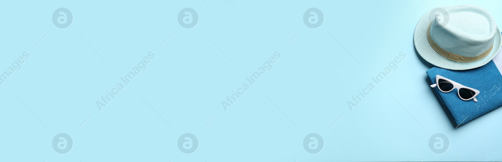 Photo of Beach accessories and space for text on light blue background, flat lay. Banner design