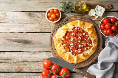 Flat lay composition of tasty galette with tomato and cheese (Caprese galette) on wooden table. Space for text